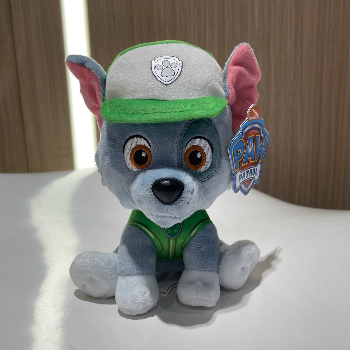 Peluche Rocky Pat Patrouille : chiot bleu, casquette verte et badge brodé.