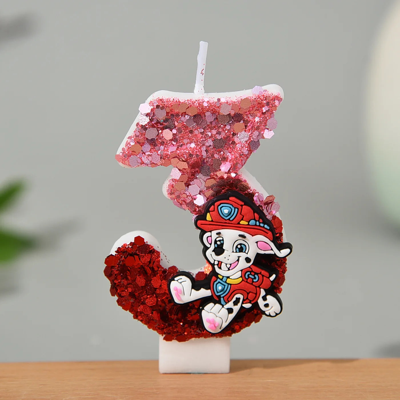 Bougie chiffre pailleté rose et rouge avec Marcus, vue de côté, sur socle blanc
