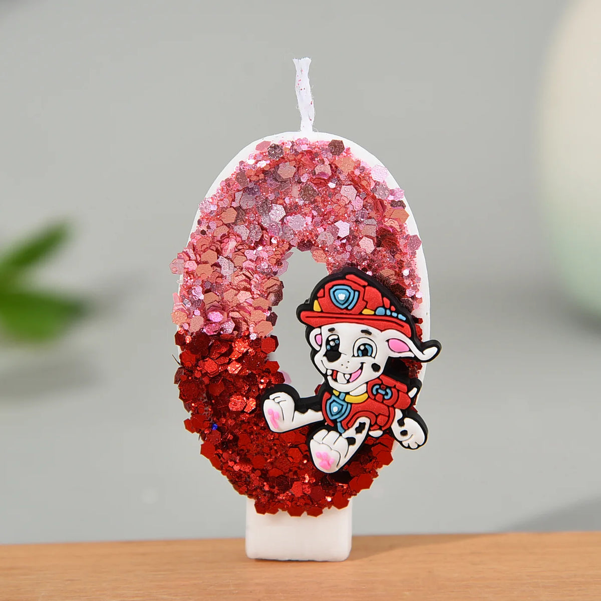 Bougie en forme de chiffre pailleté rose et rouge, avec Marcus, sur socle blanc
