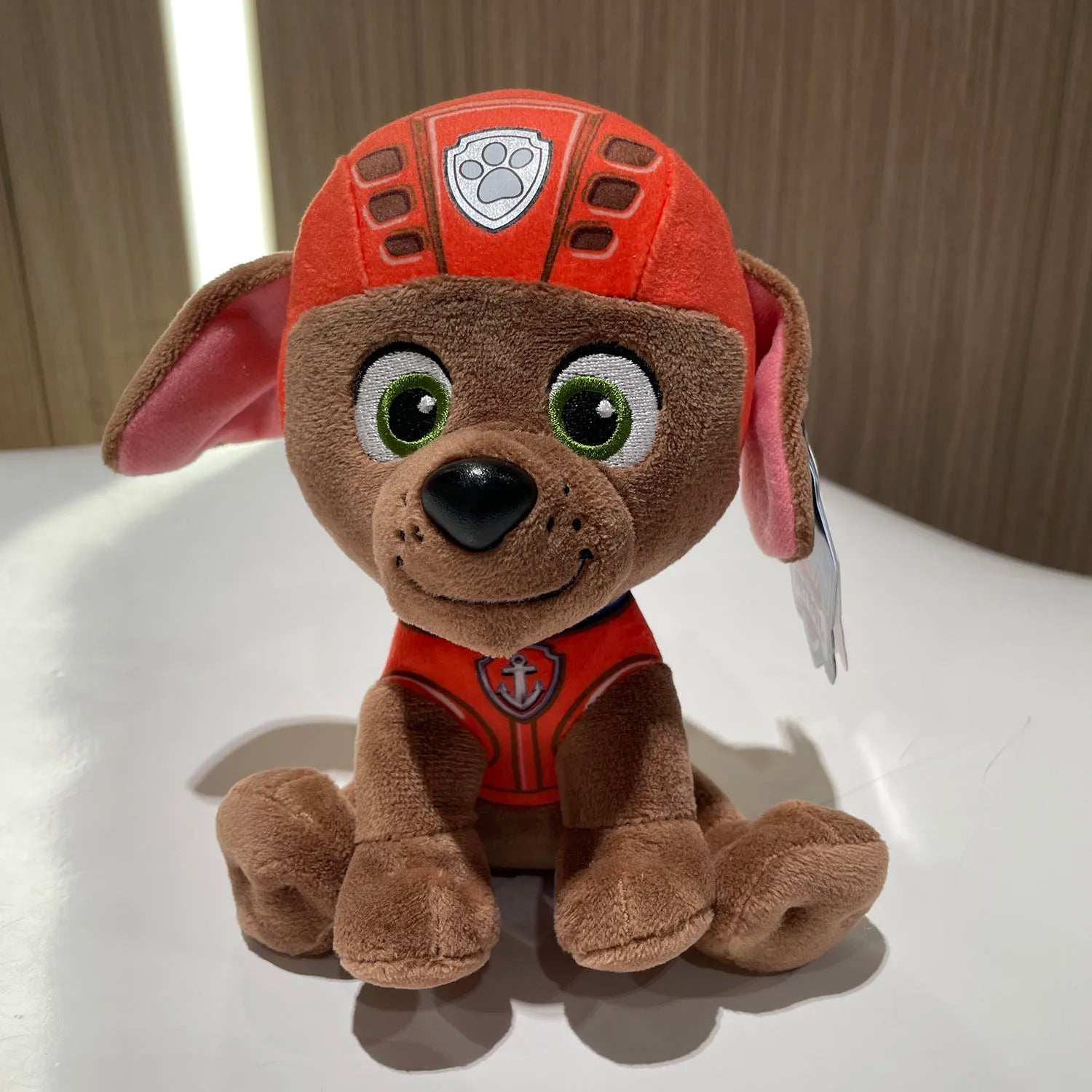 Peluche Pat Patrouille Zuma marron, tenue rouge et badges, grandes oreilles roses