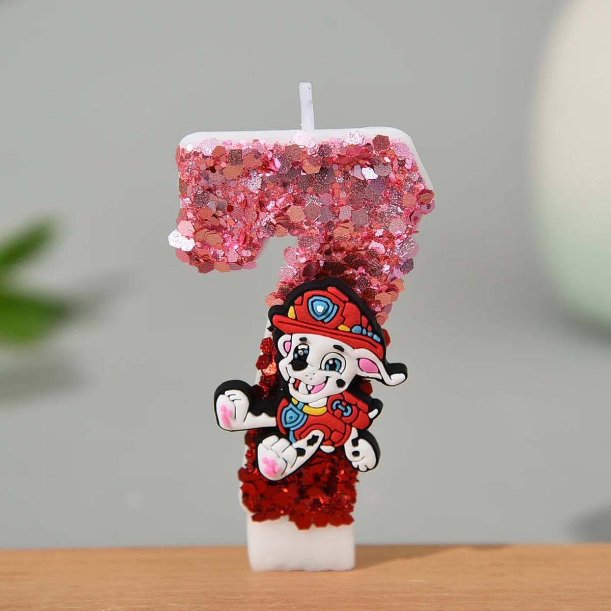 Bougie chiffre pailleté rose et rouge avec Marcus, vue rapprochée, sur socle blanc