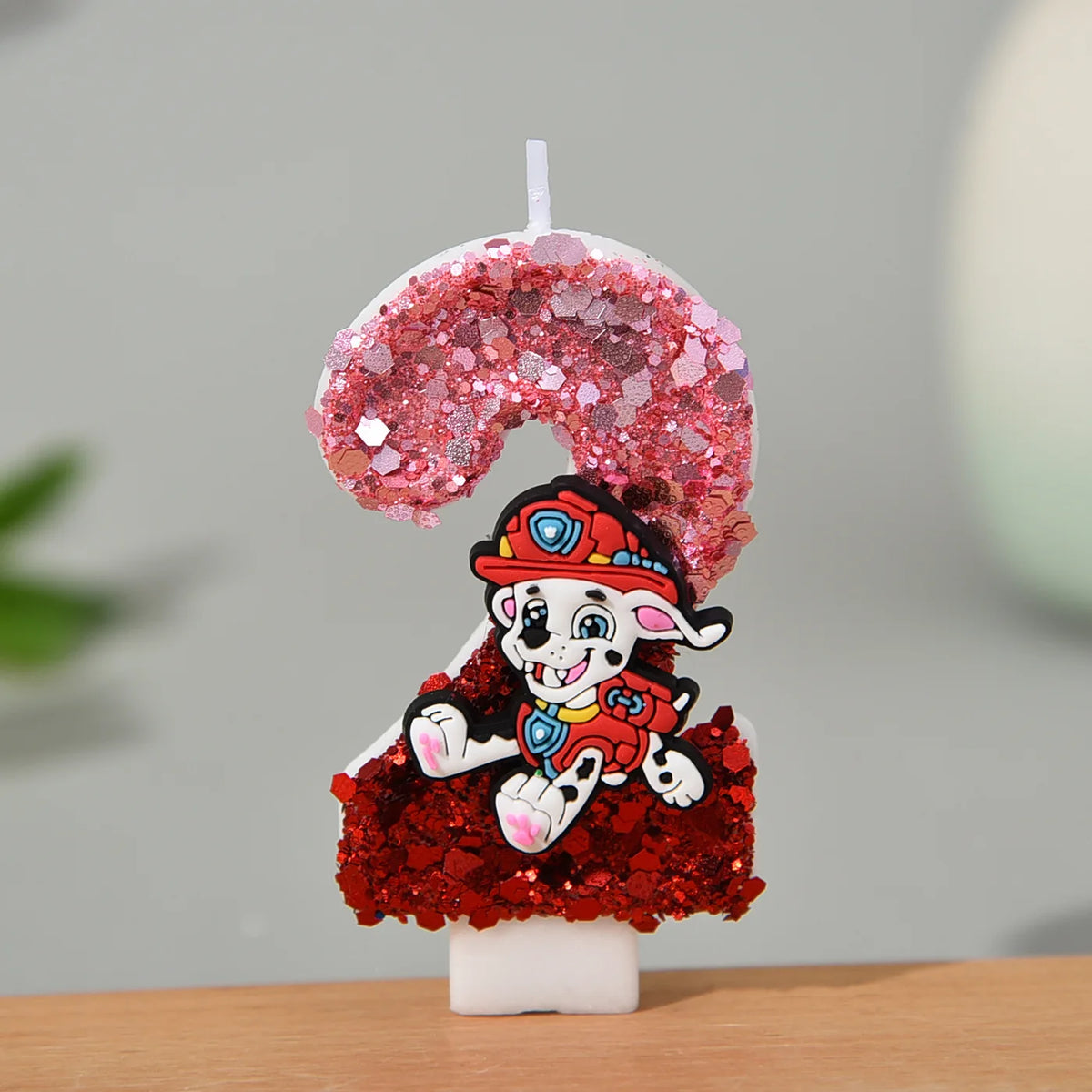 Bougie en forme de chiffre pailleté rose et rouge, personnage Marcus, sur socle blanc