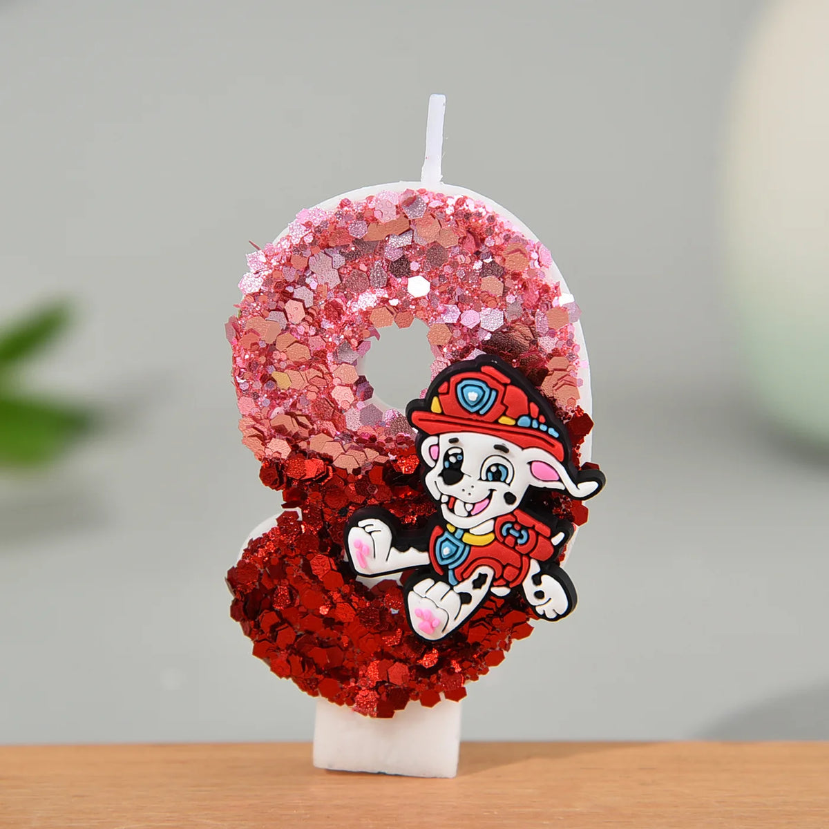 Bougie en forme de chiffre pailleté rose et rouge, personnage Marcus, sur socle blanc