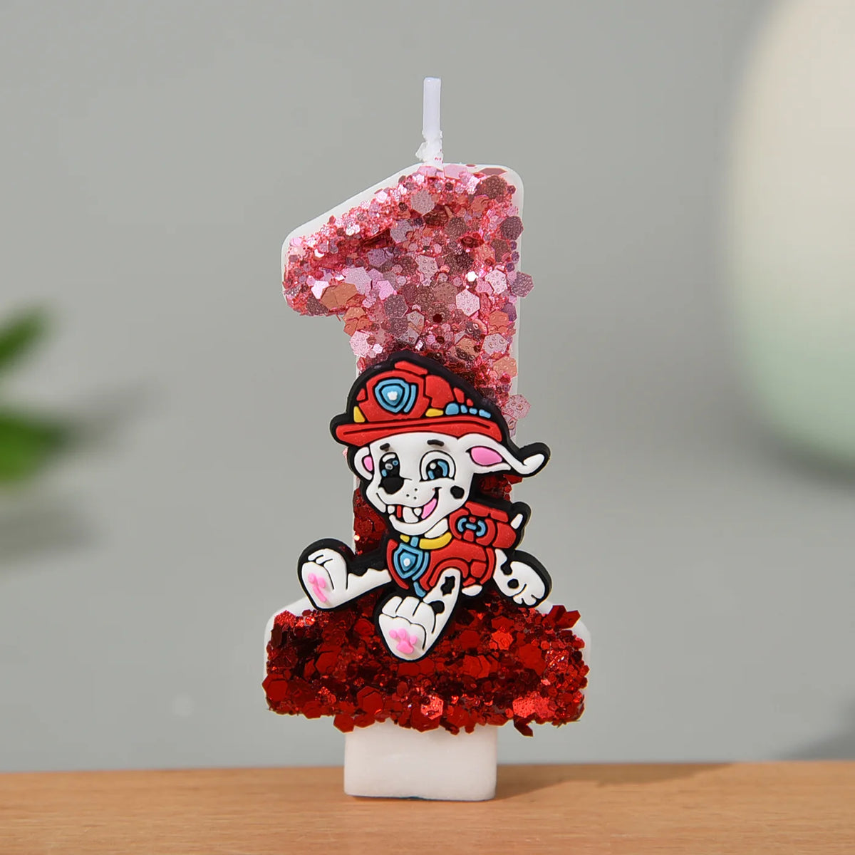 Bougie en forme de chiffre pailleté rose et rouge, Marcus en tenue, sur socle blanc